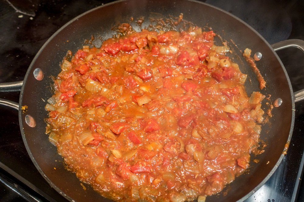 Add the tomatoes and spices to make the curry for the aloo gobi