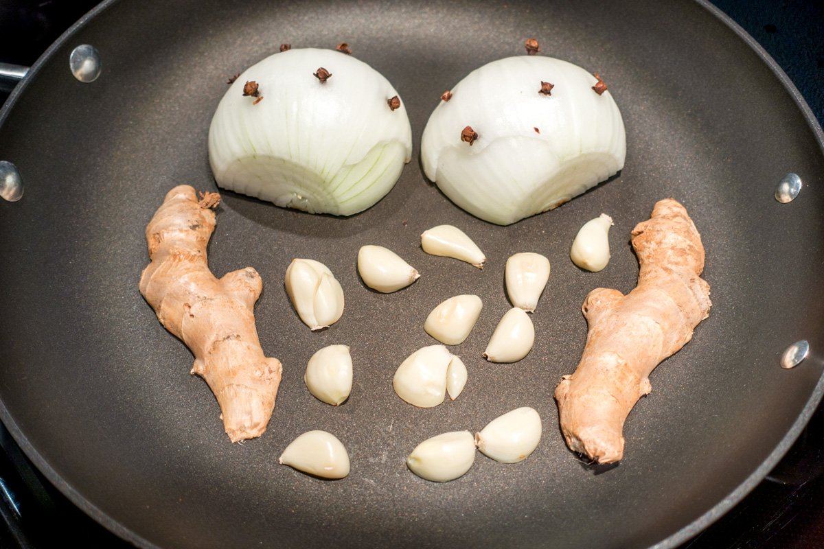 The second step in the beef pho soup recipe is charring the aromatics--onions, garlic, and ginger