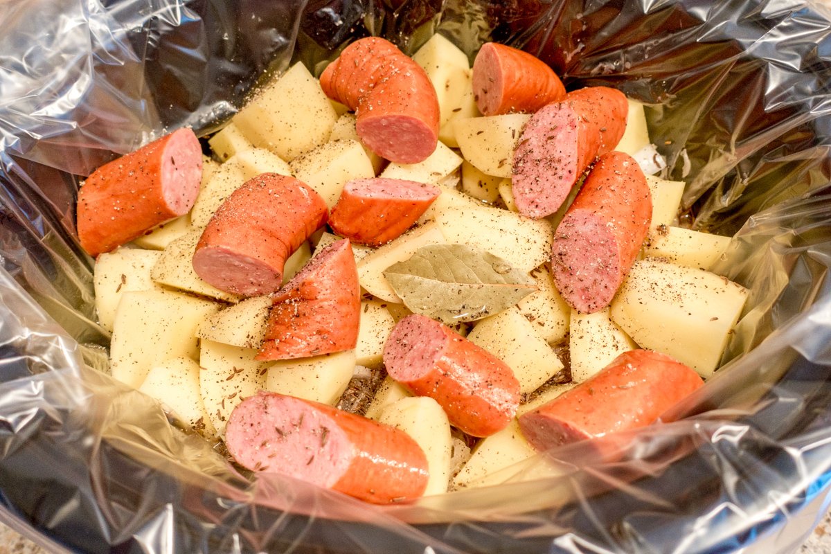 Kielbasa and sauerkraut plus potatoes and other ingredients in the pot for slow cooking