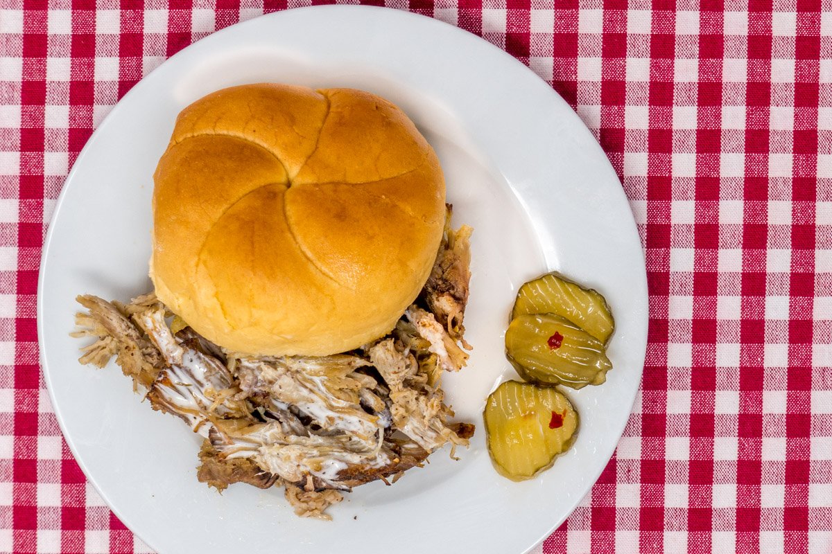 Pulled pork sandwich served with the best white BBQ sauce recipe and fire and ice pickles