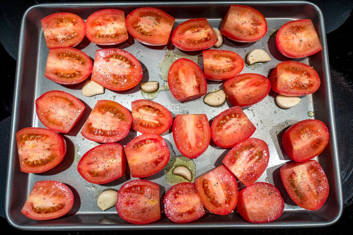 Plum tomatoes and garlic on baking sheet for tomato basil soup