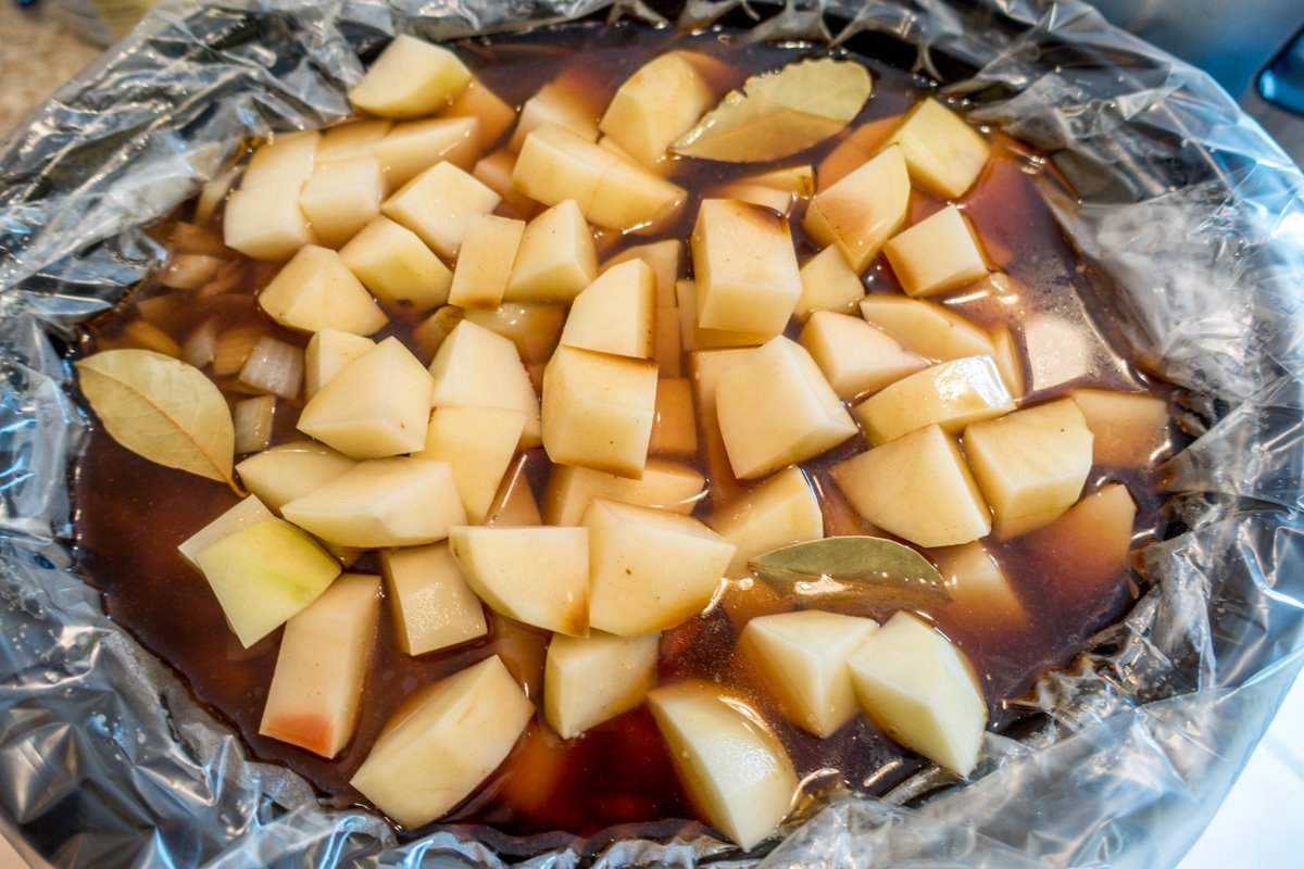 Potatoes, broth, vegetables, and bay leaf in a slow cooker