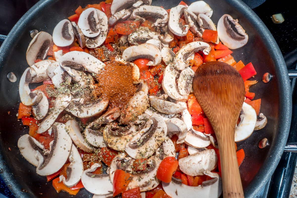 Red bell pepper, sliced mushrooms, and spices in a pan