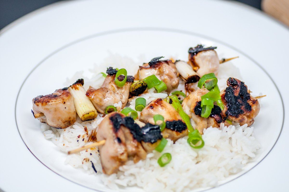 Chicken yakitori skewers over rice garnished with green onions