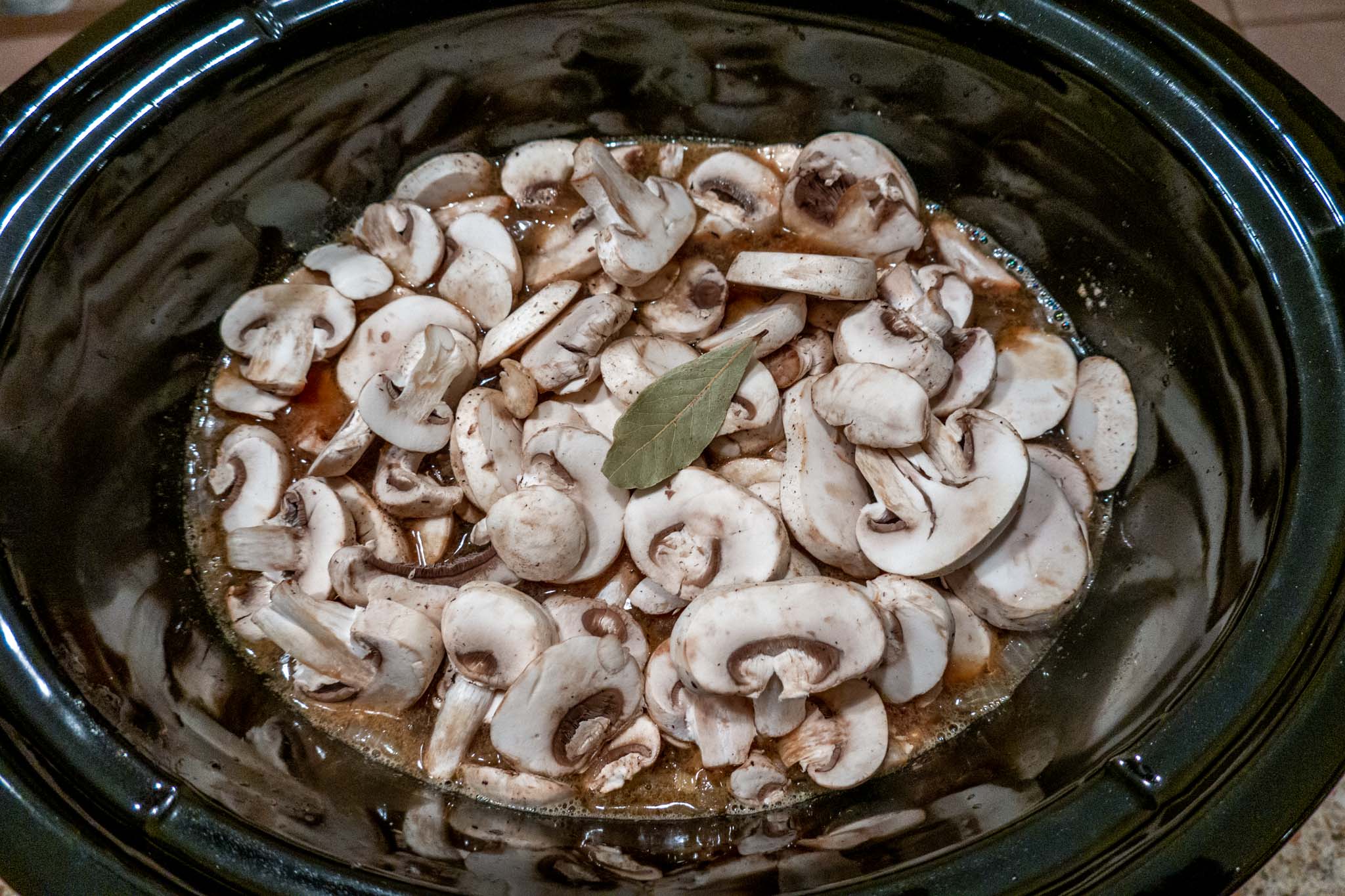 Mushrooms, bay leaf, and other ingredients combined for beef stroganoff with stew meat