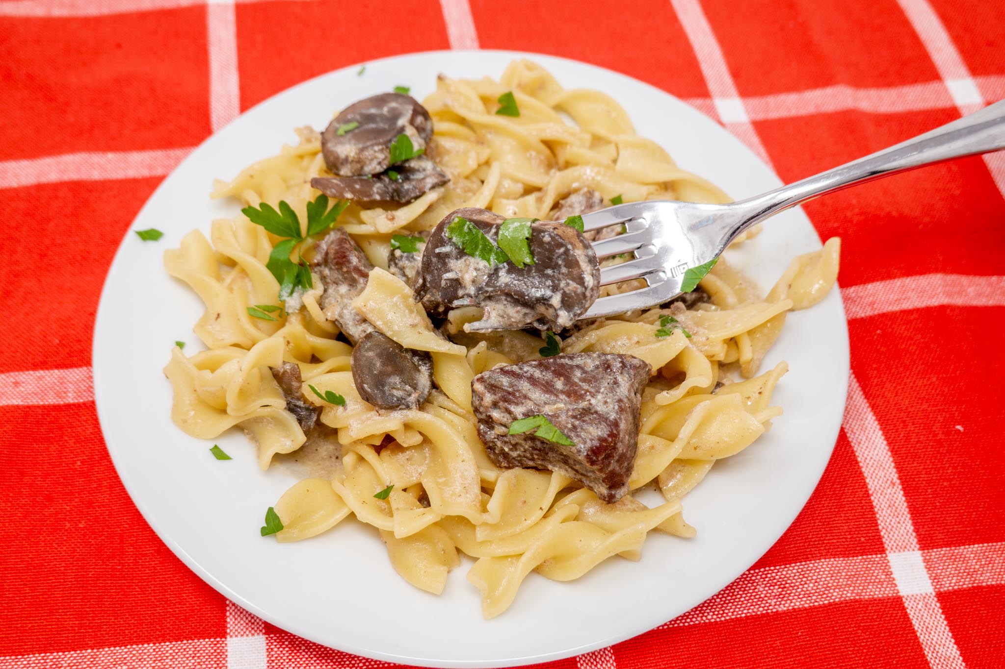 Slow cooker beef stroganoff with noodles on a plate with fork