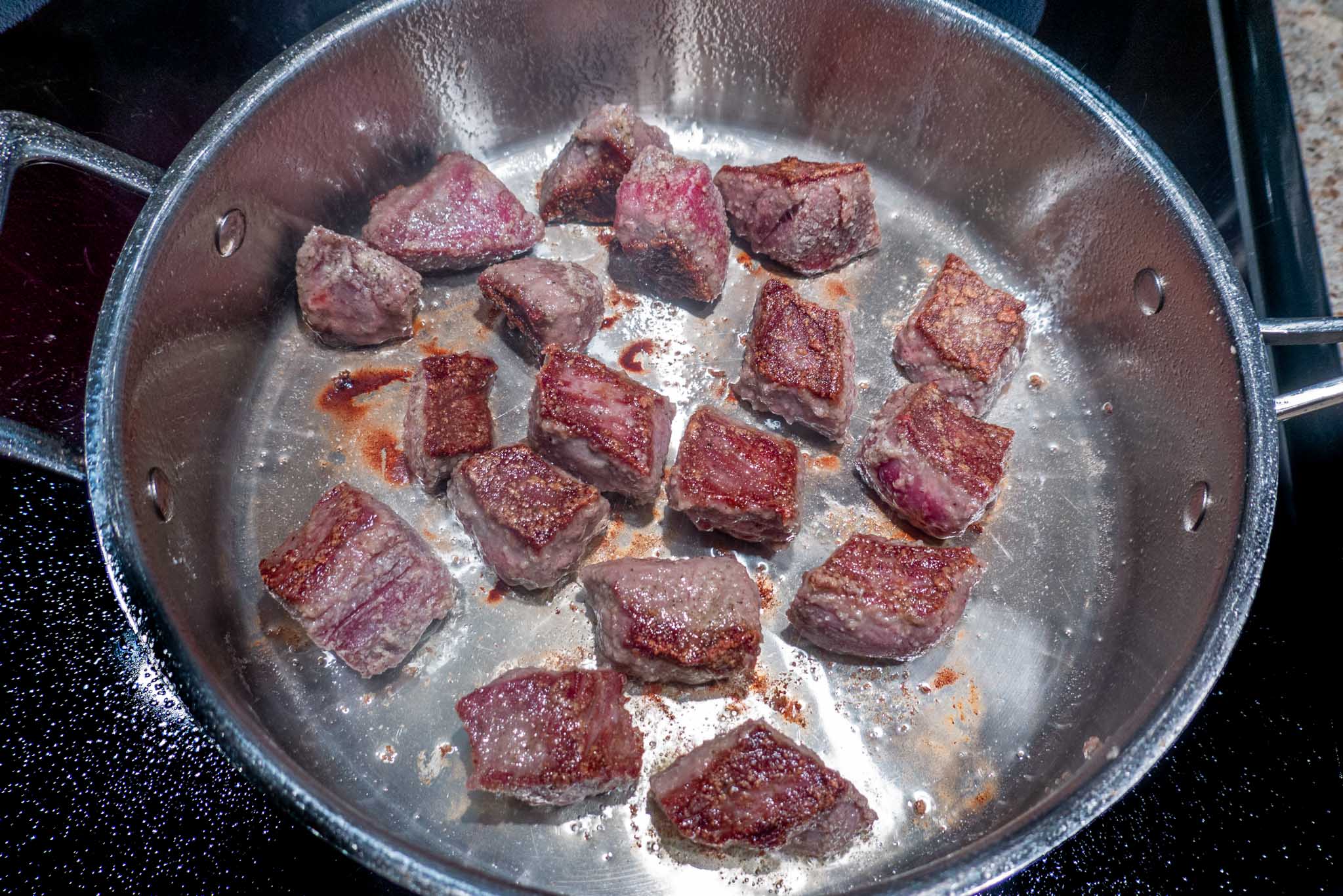 Seared cubes of beef in a pan for crock pot beef stroganoff
