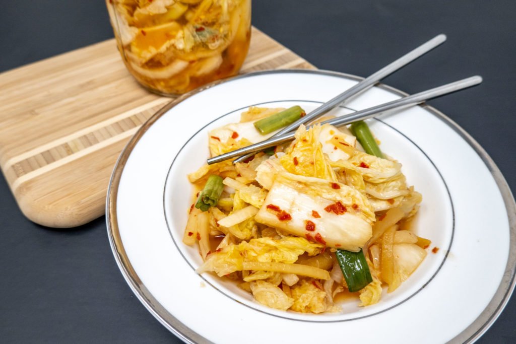 Bowl of baechu kimchi, a dish of fermented vegetables with the right amount of spice, on a table with chopsticks