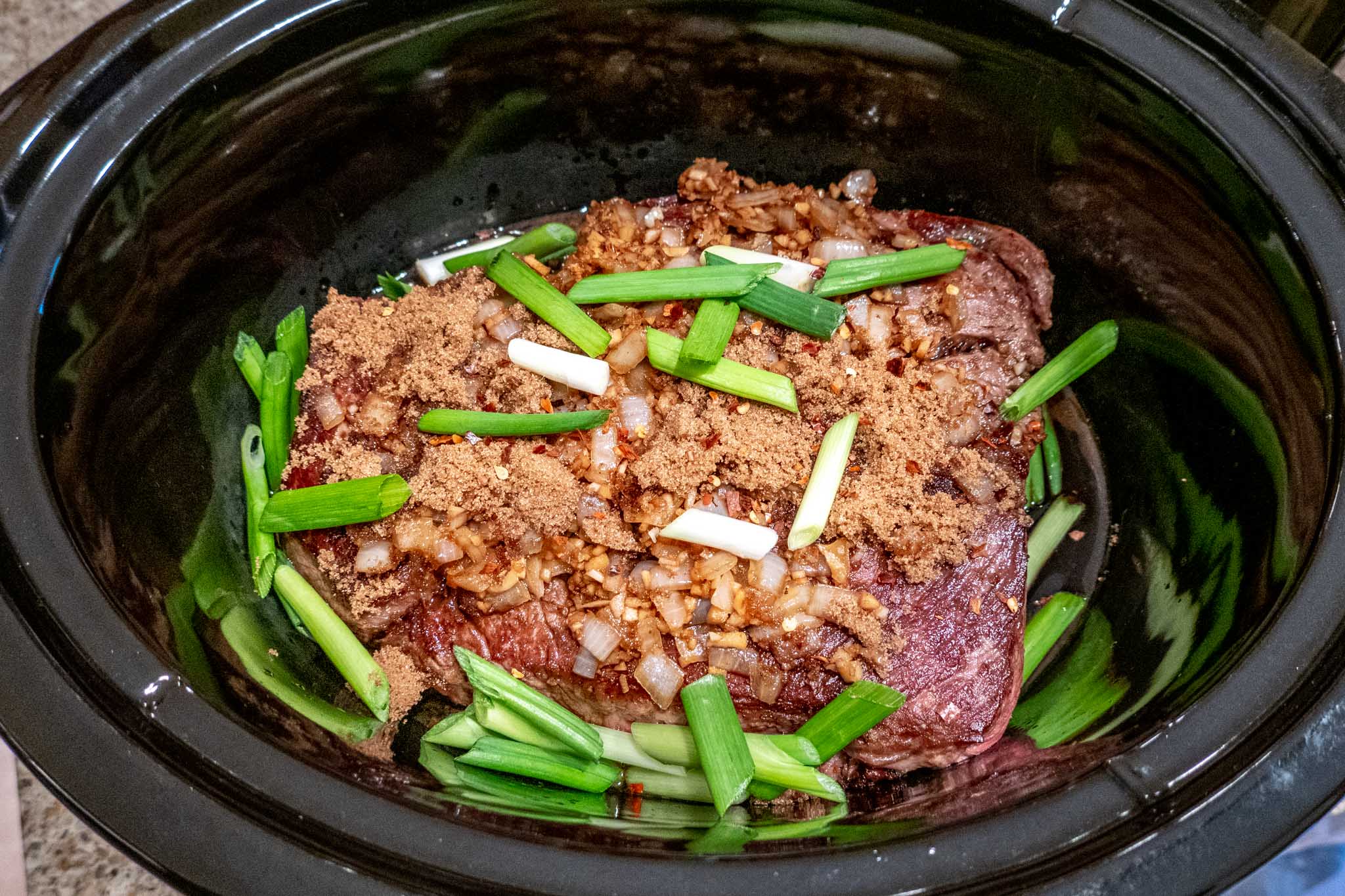 Beef with brown sugar, scallions, and other ingredients in slow cooker