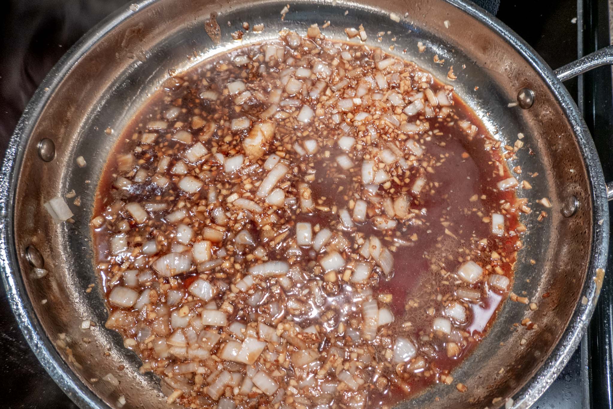 Sauteed garlic, onion, and ginger in pan with sauce 