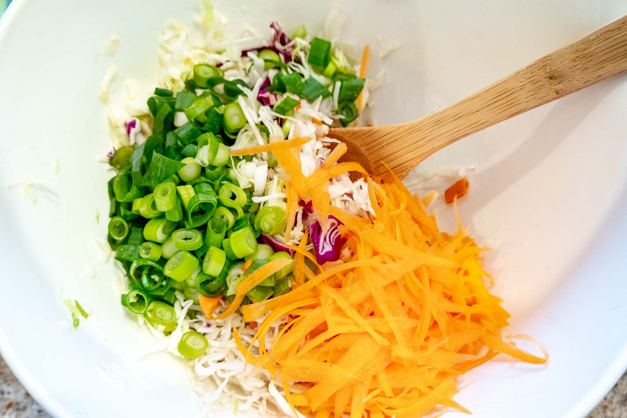 Chopped cabbage, carrots, and scallions in a bowl