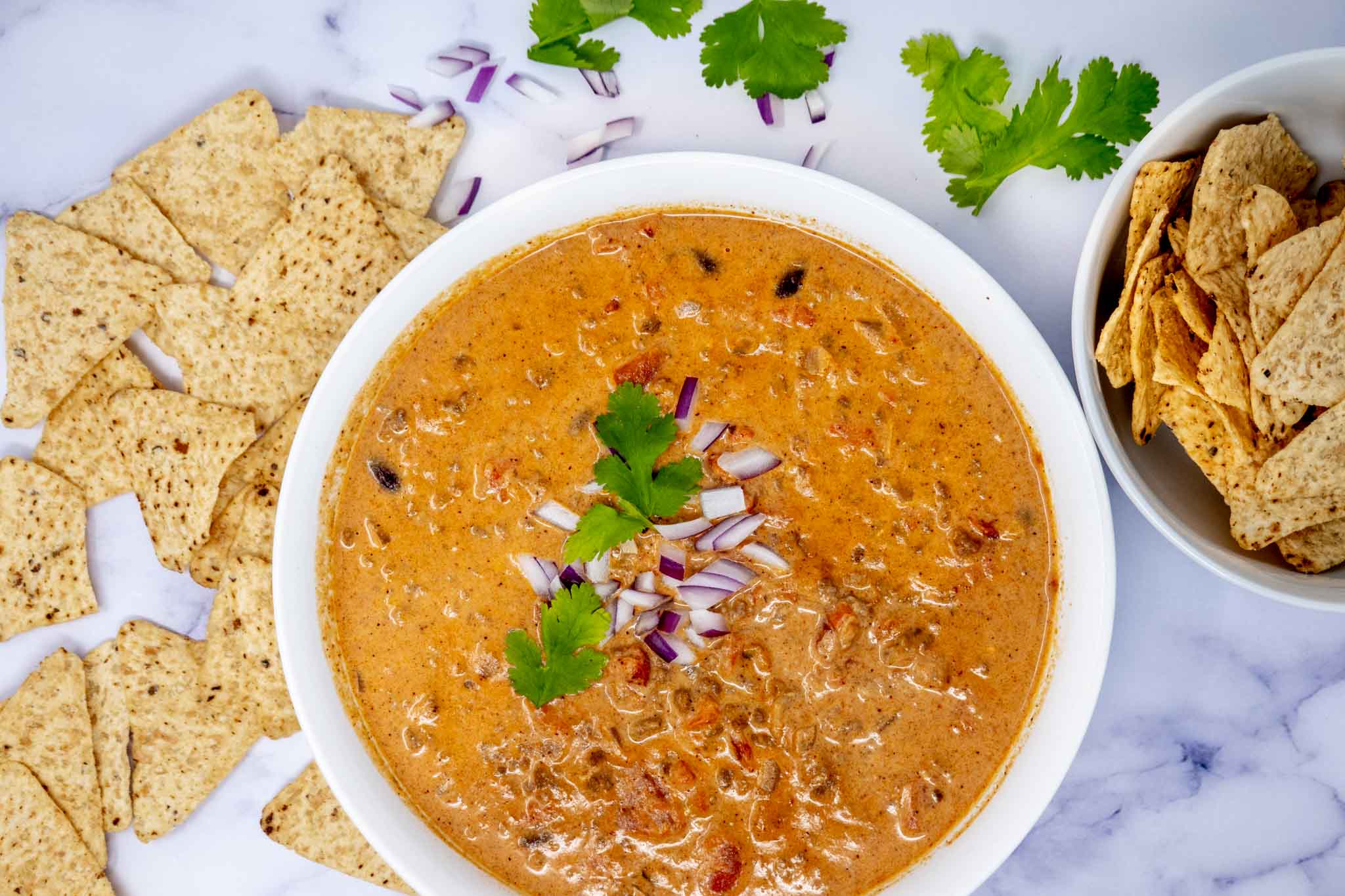 Bowl of chili cheese dip beside tortilla chips