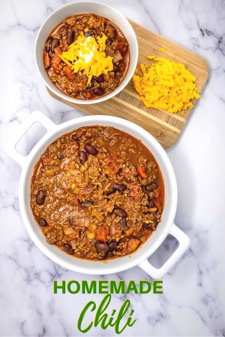 Homemade chili in a bowl beside a pile of shredded cheese